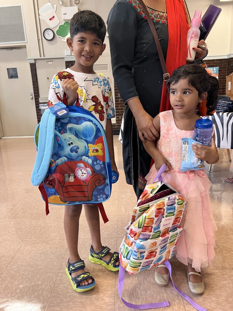 Sean and his sister receive stocked backpacks, courtesy of The Child Center's backpack drive, before they start school and afterschool at P.S. 56 in Richmond Hill, Queens