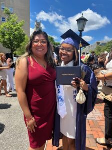 The author, Madison, poses in a cap and gown on high school graduation day with her therapist, Jennifer Trujillo-Armijo, LMSW, from her school's school-based mental health center.