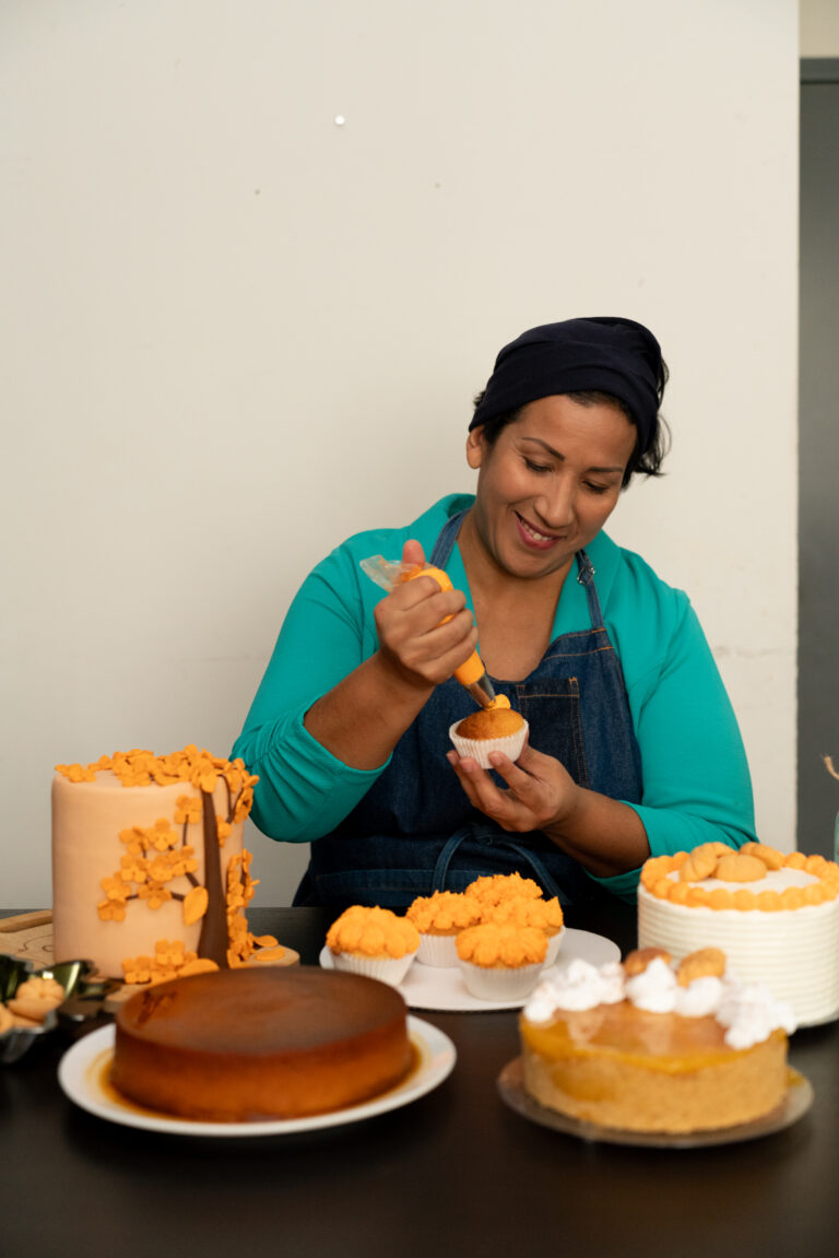 Noelia, a Cash+Community Works participants is decorating a cake for her business, Noelia's Sweets.