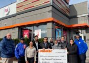 Omar Kazi and other Dunkin' and community members pose with a giant check.