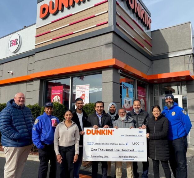 Omar Kazi and other Dunkin' and community members pose with a giant check.