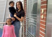 Julissa poses outside on her doorstep with her two young children.