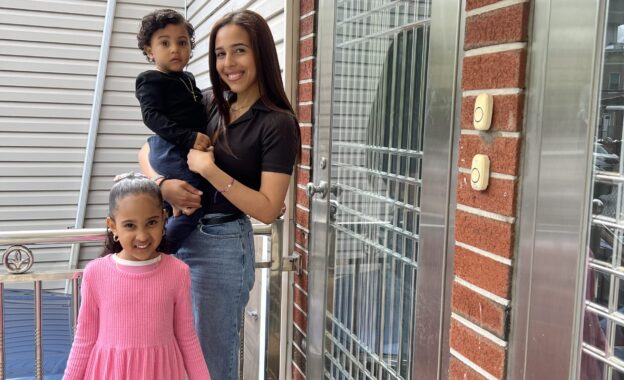 Julissa poses outside on her doorstep with her two young children.