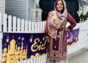 Mehak stands near an Eid sign on a fence