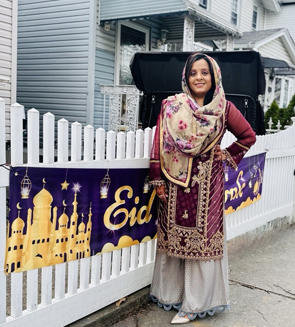 Mehak stands near an Eid sign on a fence