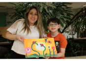A mom and her third-grade son hold up a painting where there are two halves that make a whole.