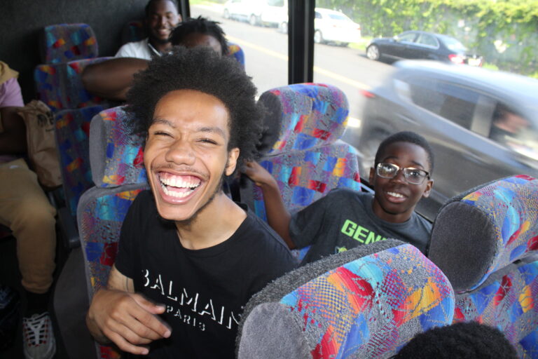Dionte is sitting next to a fifth-grade participant. Dionte is laughing and the participant is smiling.