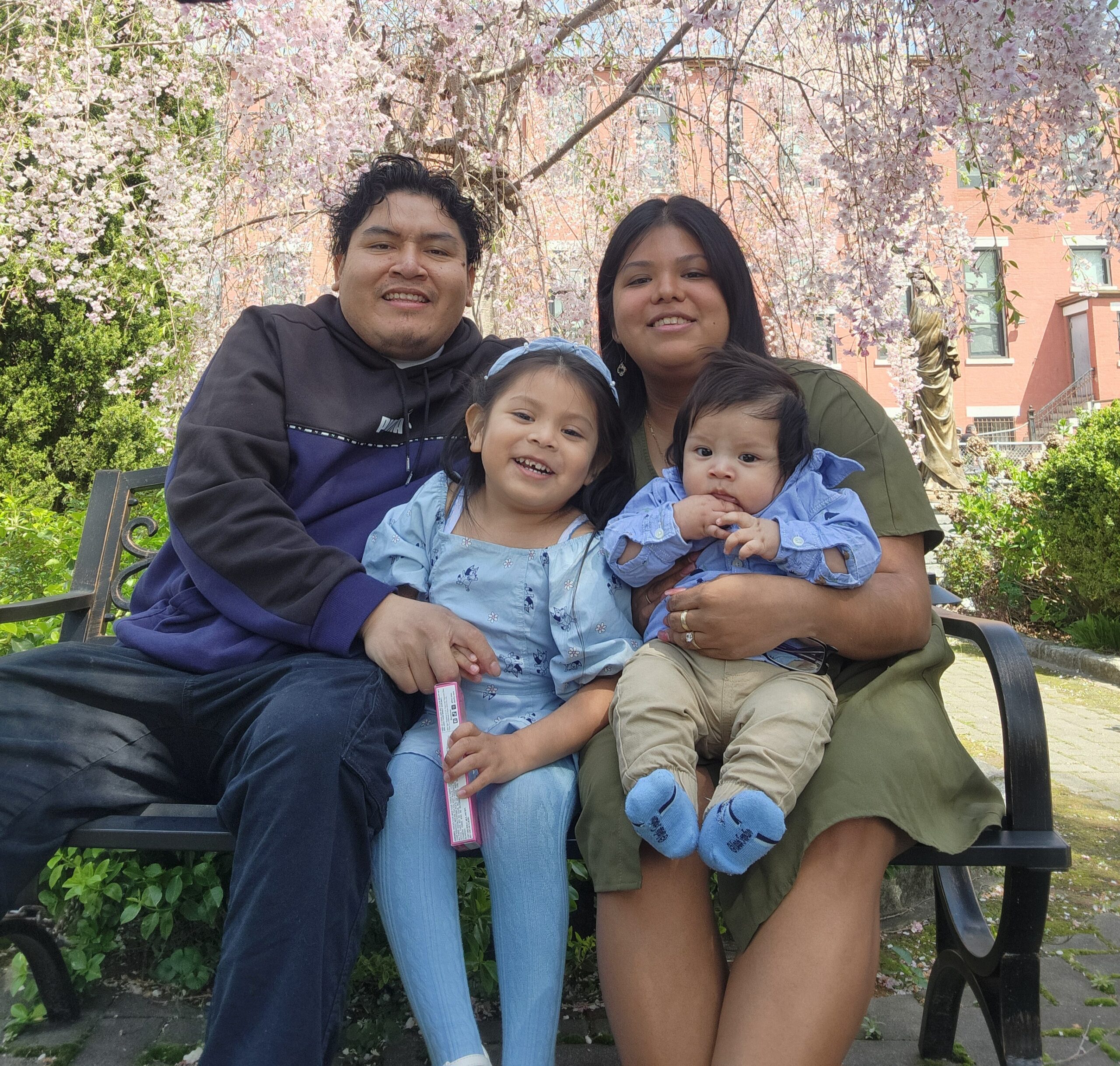 Guadalupe and her husband and two young children, who were Early Head Start students, sit on a bench outside.
