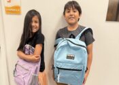 A girl and a boy carry their new backpacks in front of them, courtesy of the Child Center backpack drive.