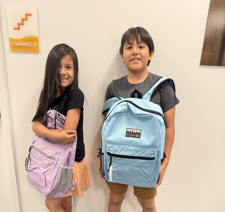 A girl and a boy carry their new backpacks in front of them, courtesy of the Child Center backpack drive.