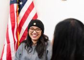 Christie, a client of Military Services, sits smiling with an American flag behind her.